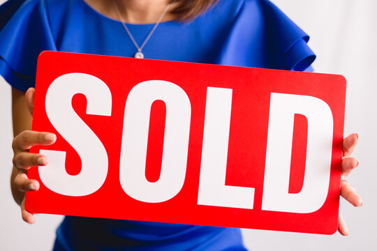 realtor holding a sold sign 