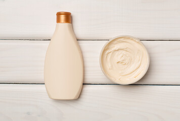 Shower gel and body cream on wooden background, top view
