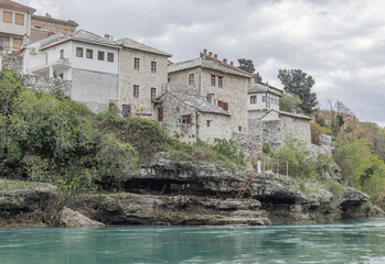 Looking across a turquoise river at buildings on a river bank