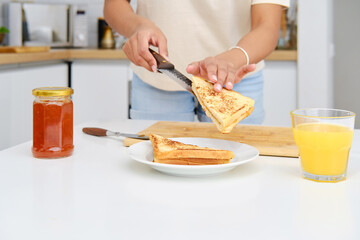 Closeup view of female hands putting piece of sweet toast on a plate