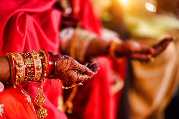 Closeup of hands with henna tattoos during an Indian traditional wedding ceremony, kanyadan ritual