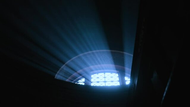 Bright sunlight breaks through the semicircular window with a lattice into a dark high room. Feelings of fear and hope.