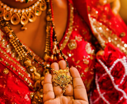 The hand of the groom holding the Indian marriage necklace after tied it around the bride's neck