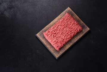 Fresh raw mince with spices and herbs on a dark concrete background
