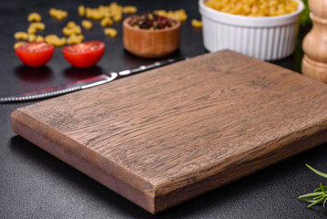 A wooden cutting board with a kitchen knife with spices and herbs