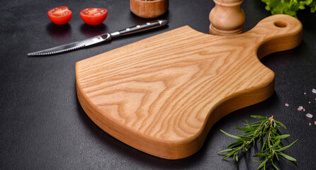 A wooden cutting board with a kitchen knife with spices and herbs