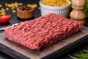 Fresh raw mince with spices and herbs on a dark concrete background