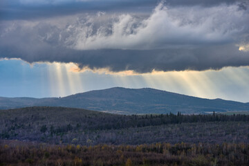 Thundercloud and rays of the sun on a mountain in mountainous forests