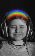 Portrait of a little girl in headphones with a rainbow close-up. Pastime