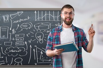 Smiling millennial bearded guy teacher stands near blackboard and teaches social distance study and knowledge during.