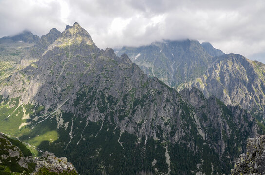 Landscape with rocky mountain ridge and sharp peaks hidden by clouds. High Tatras, Slovakia