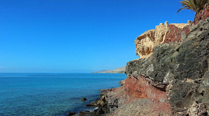 View along the cliff at Costa Calma on the island of Furteventura in the Canary Islands with a blue, cloudless sky and clear water