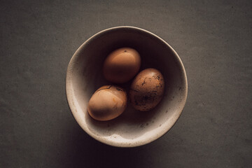 fresh barn eggs in beige ceramic bowl strong shadows