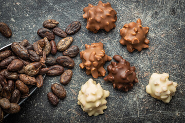 Chocolate truffles and cocoa beans. Sweet pralines on black table.