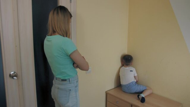 Woman scolds her little son, boy crying in corner, resentment and quarrel between mother and child, kid ignores mother. Family scandal, disagreement, soreness feeling