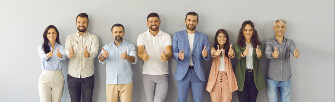 Group of smiling ambitious confident young, mature, senior people giving thumbs up. Banner with studio portrait of successful modern male and female business team standing together doing like gesture