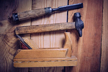 Set of carpentry tools hammer, chisel and plane on a wooden background.