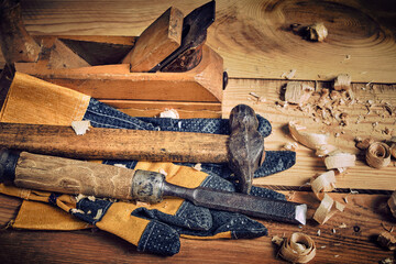 Carpenters tool kit, hammer, chisel and plane with gloves wooden background.