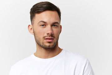 Obraz premium Closeup portrait. Flirted tanned handsome man in basic t-shirt raises eyebrow look at camera posing isolated on white studio background. Copy space Banner Mockup. People emotions Lifestyle concept