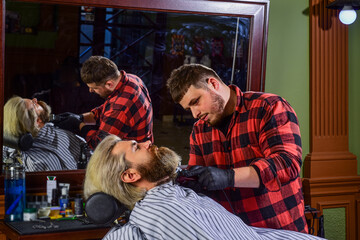 Making his beard perfect. stylish man beard. shaving. Hairstylist in barbershop. man in hair salon with hipster haircut. beard and mustaches. Professional hairstylist in barbershop interior