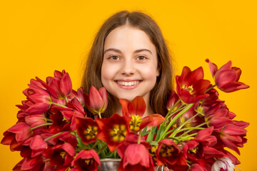 positive girl hold spring tulip flowers on yellow background