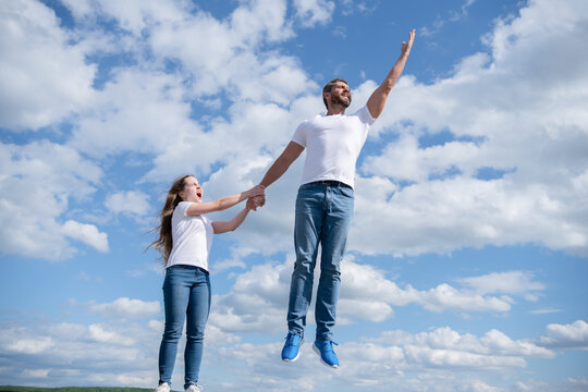 daughter hold her dad jumping in sky