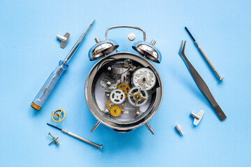 Broken alarm clock top view. Watch mechanism and watchmaker tools