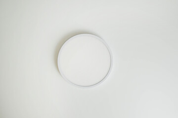 Round, minimalist, simple lamp on a white ceiling. A lamp that does not attract attention.
