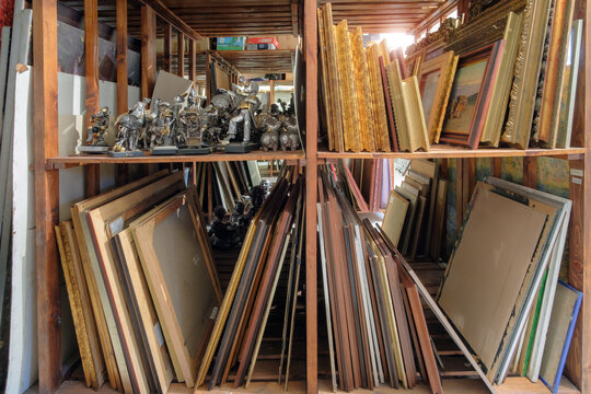 Wooden shelves full of pictures, frames and art equipment. Art gallery storage