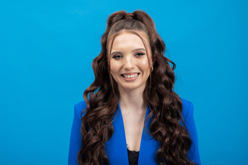 Attractive, excited young girl in casual clothing, isolated on blue background, looking into camera.