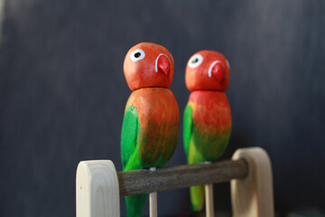 Naklejka premium pair of funny lovebird parrots,carved wooden toy close-up
