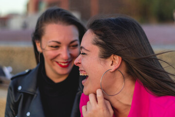 Couple of lesbian girls laughing, one with a purple shirt and the other with black clothes and red lips. Concept: LGBT