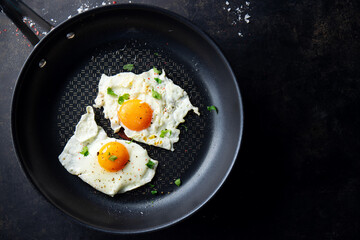 Fried eggs with parsley on pan