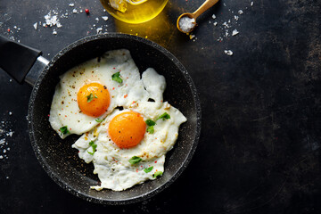 Fried eggs with parsley on pan