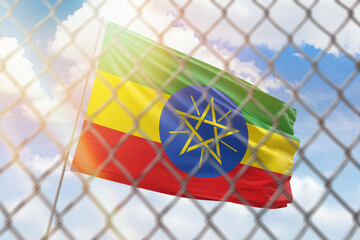 A steel mesh against the background of a blue sky and a flagpole with the flag of ethiopia