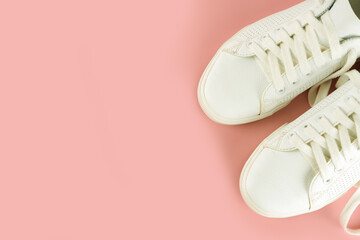 Pair of white sneakers on pink background. Unisex shoes, stylish white sneakers. Top view, flat lay, mockup with copy space for text