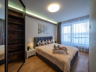 Modern interior of bedroom in luxury apartment. Breakfast on bed.
