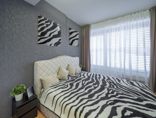 Modern interior of bedroom in luxury cottage. Zebra print bedspread.