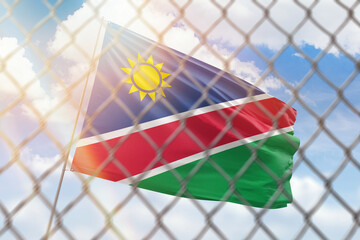 A steel mesh against the background of a blue sky and a flagpole with the flag of namibia