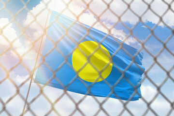 A steel mesh against the background of a blue sky and a flagpole with the flag of palau