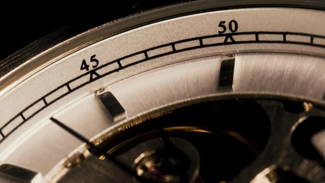 Macro sweeping seconds hand along a skeletonized mechanical watch dial