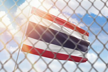 A steel mesh against the background of a blue sky and a flagpole with the flag of thailand