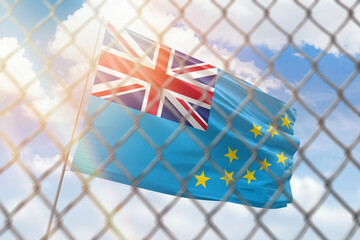 A steel mesh against the background of a blue sky and a flagpole with the flag of tuvalu