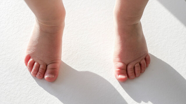 View of bare baby feet dancing on white floor