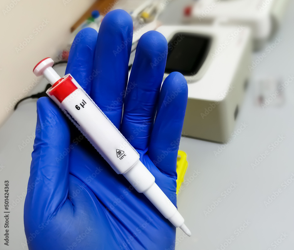 Poster hand holding micro pipette in laboratory. microliter pipette.