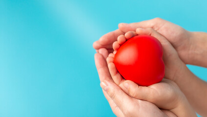 A red heart in female and child hands. The concept of the war in Ukraine. Valentines day or healthcare, medical concept. Peace on the world