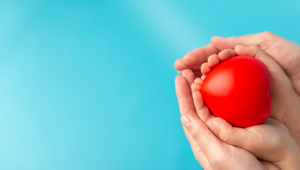 Adult and child hands holding red heart, health care, love, organ donation, family insurance and CSR concept, world heart day, world health day, foster home care