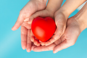 Adult and child hands holding red heart, health care, love, organ donation, family insurance and CSR concept, world heart day, world health day, foster home care