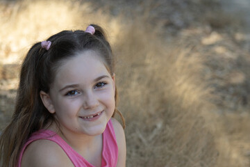 girl with fuchsia t-shirt and pink scrunchie with two pigtails on a blurred background 