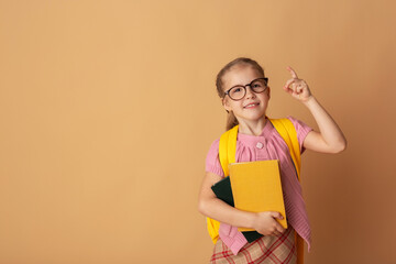 Cheerful smiling little girl with books and backpack smiling and looking at camera. School concept. Back to School